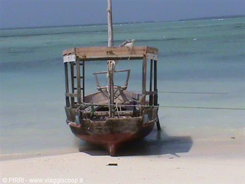 Old wooden boat stranded on white sand in front of turquoise sea