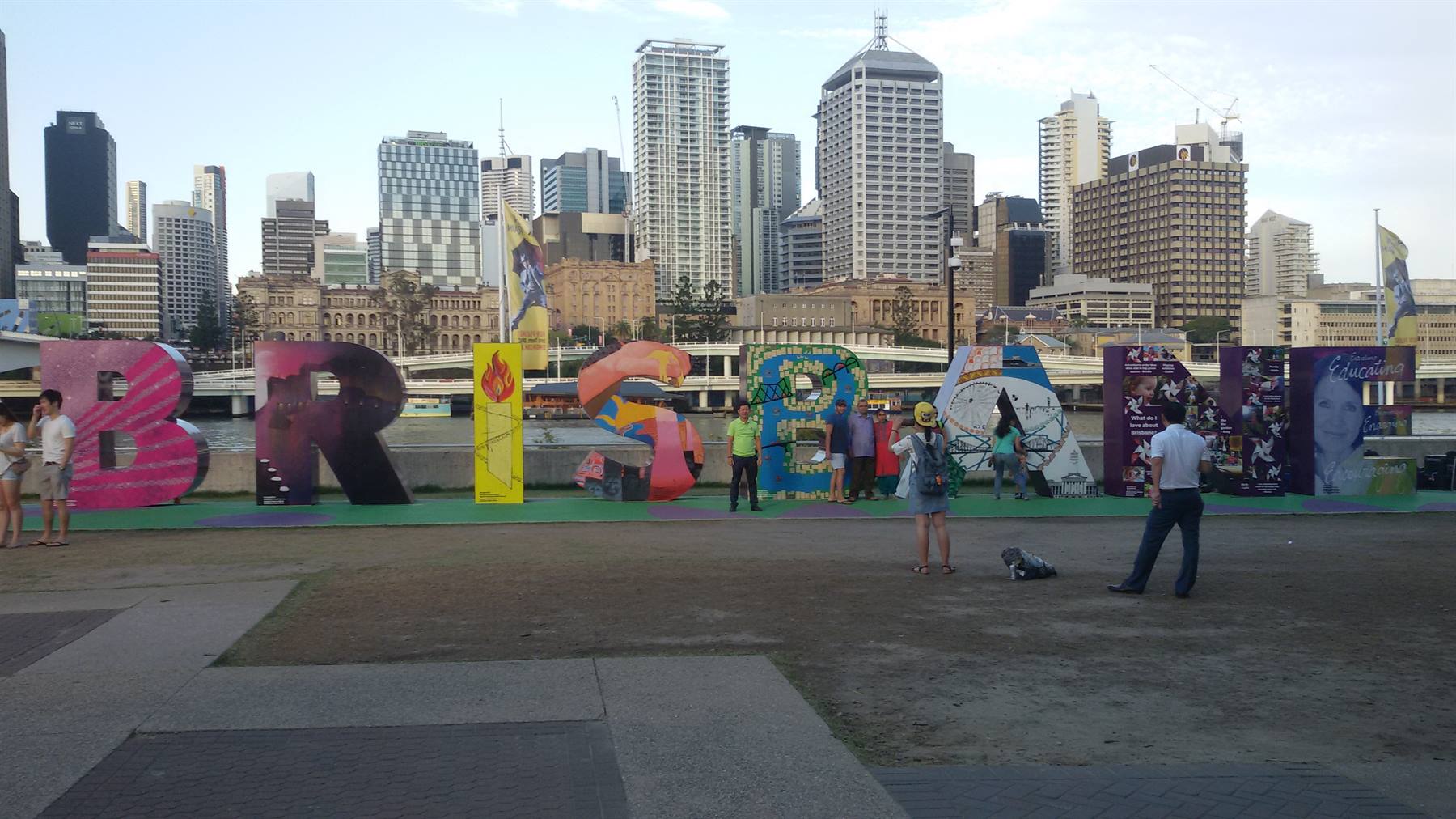 Giant colorful Brisbane sign with tourists in front of city skyscrapers