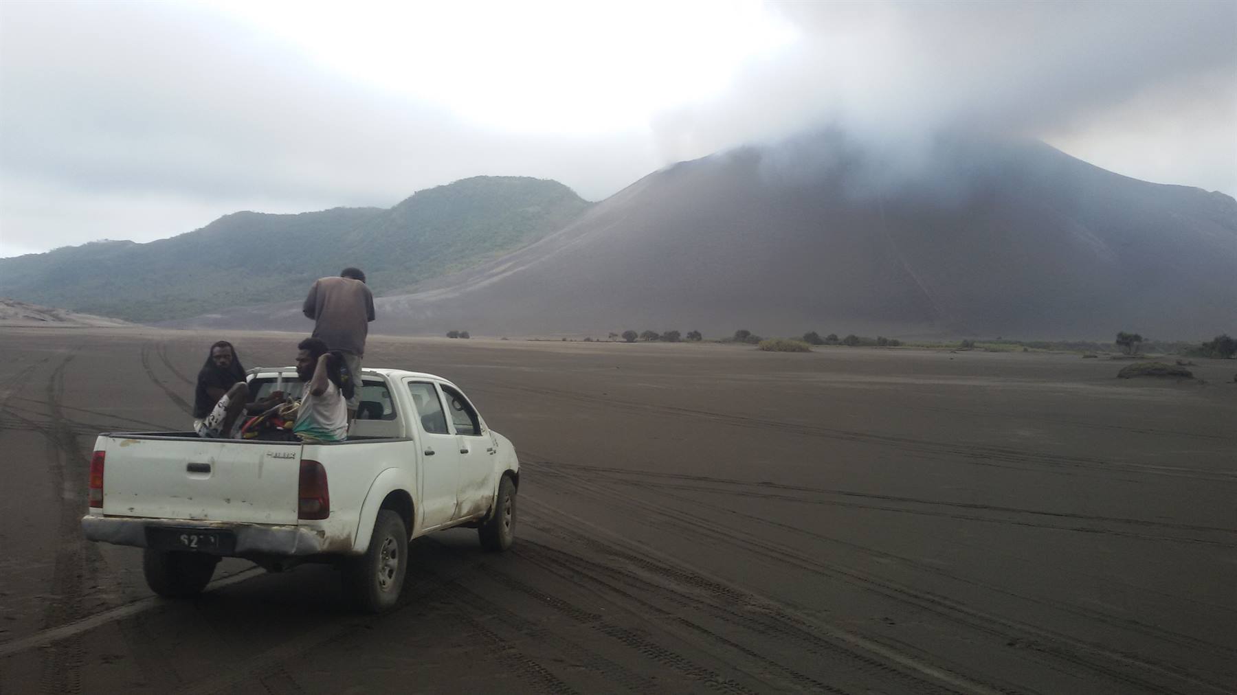 Turisti su un fuoristrada bianco nella sabbia vulcanica davanti al Bromo fumante
