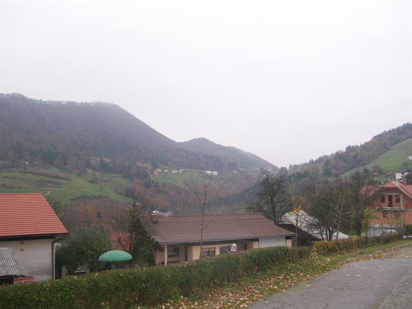 Red roofs and houses among wooded hills under grey sky, green garden umbrella