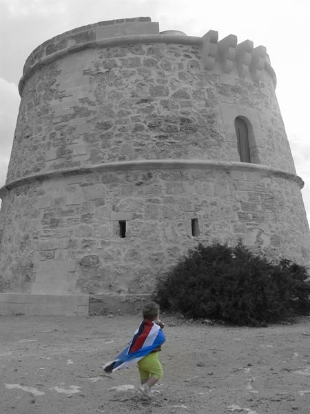 Child with Dutch flag runs in front of an old stone defense tower
