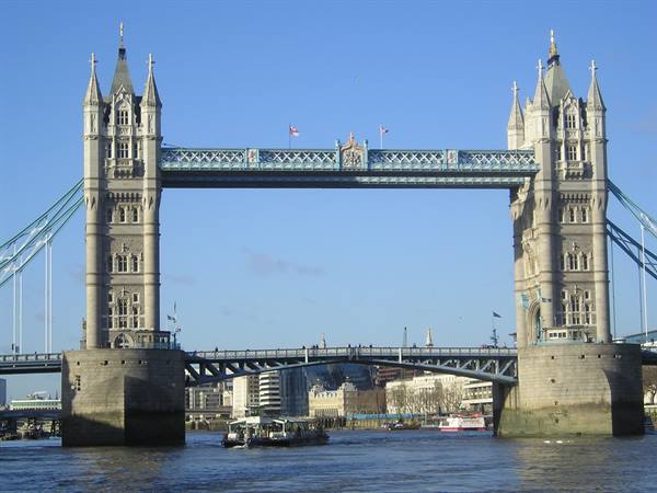 Tower Bridge in London, stone towers over the Thames with boats in sunlight