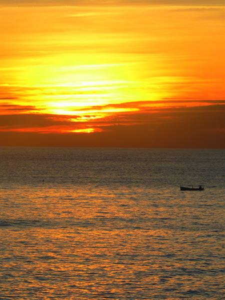 Small fishing boat alone on the golden sea under the low sun