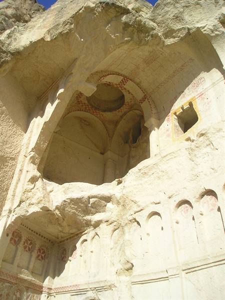 Rock-cut church carved in stone at Göreme, red frescoes under the sun