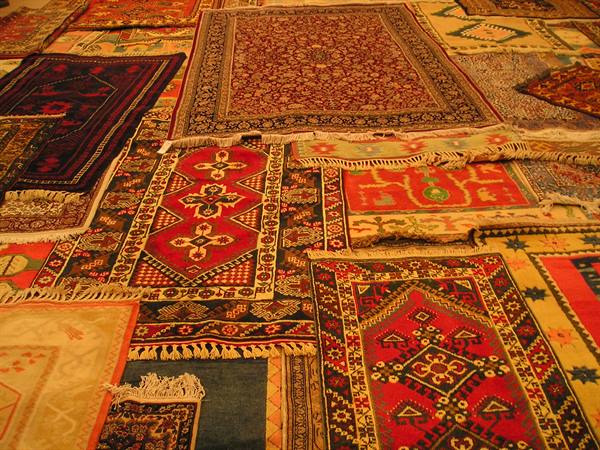 Oriental carpets overlapping, warm light on red and cream patterns