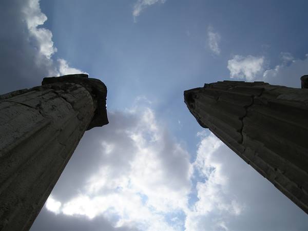 Ancient cracked stone columns rising into a white cloudy sky