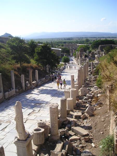 Tourists walk among marble columns on the ancient street of Ephesus
