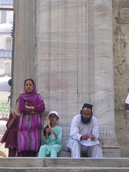 Family in traditional clothes sitting beside a marble column at the Blue Mosque