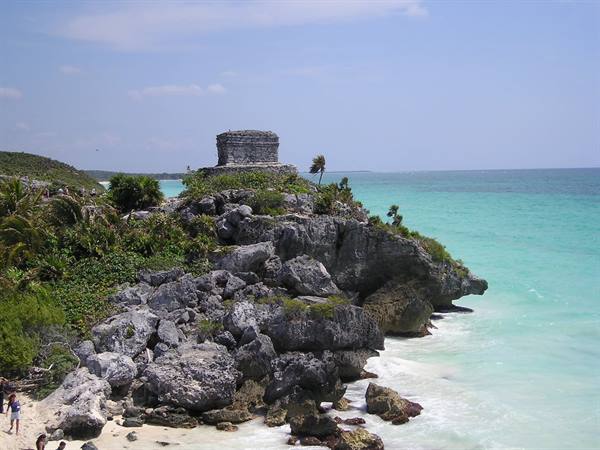 Ancient Mayan stone temple on Tulum cliff, turquoise sea and tropical vegetation