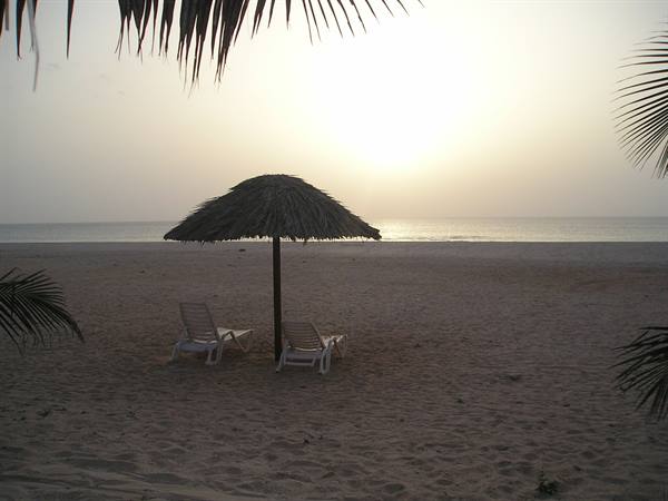 Thatched umbrella with two white loungers on a sandy beach