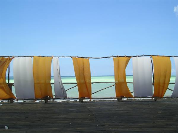 Orange and white fabrics drying on a rope in front of the sea