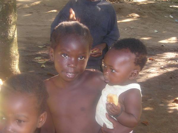 Children in village sunlight, one clutching fruit in hand