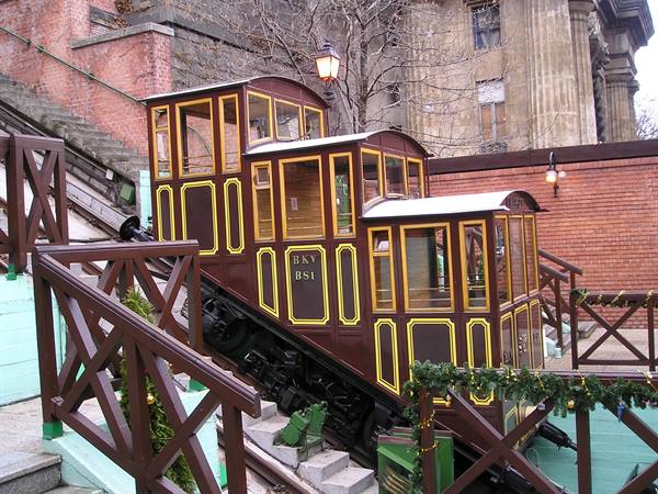 Wooden carriages of the Budavári Sikló funicular on rails by brick walls