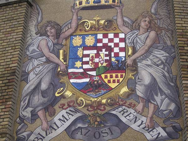 Mosaic of crowned Hungarian coat of arms held by two angels on brick wall