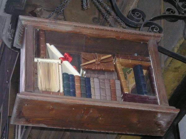 Wooden bookshop sign with antique books hanging from iron chains