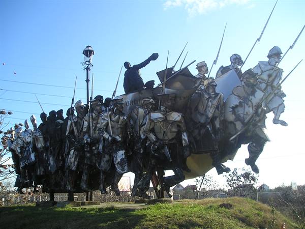 Metal sculpture of marching soldiers with rifles under blue sky