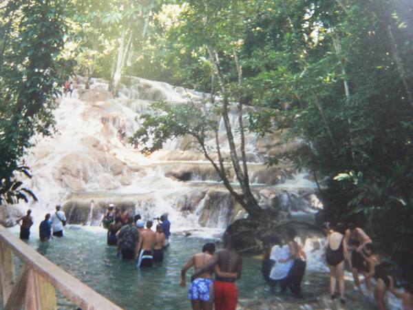 Tourists in swimwear climb the terraced falls at Dunn's River Falls