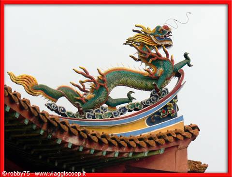 Green and golden ceramic dragon on curved temple roof