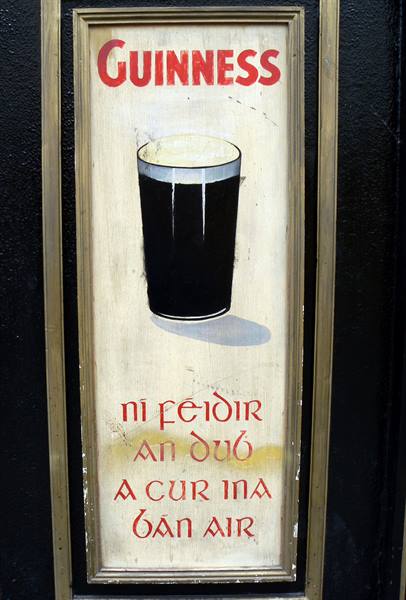 Painted Guinness pub sign with a black pint and Gaelic lettering