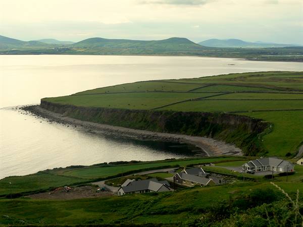 Grassy cliffs and white houses above a bay along the Ring of Kerry
