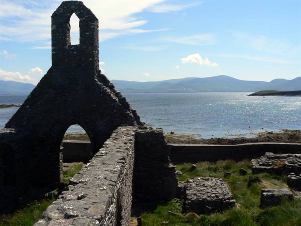 stone church ruins facing the sparkling sea and distant hills
