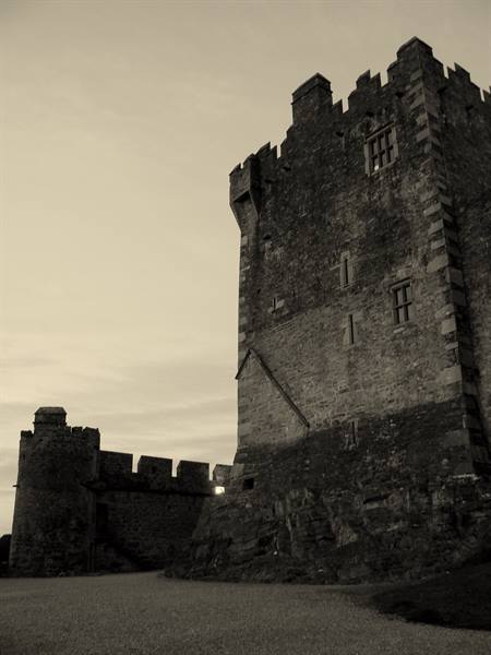 Medieval stone tower with battlements and defensive walls under grey sky