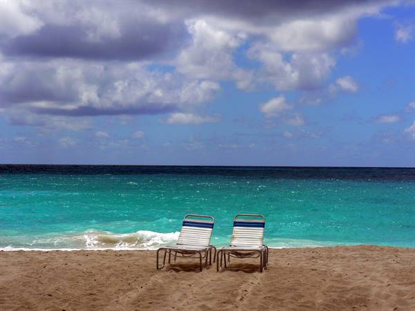 Two empty loungers on the sand before the turquoise sea