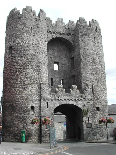 Medieval grey stone gate with two crenellated towers, arched town entrance