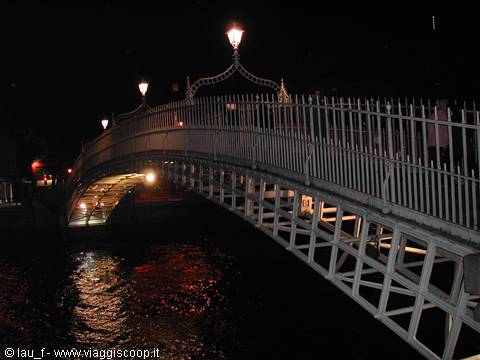 The white iron Ha'penny Bridge lit at night over the River Liffey, Dublin