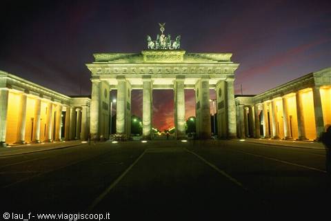 Brandenburg Gate illuminated at night in Berlin, purple sky and empty road