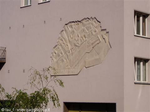 Stone relief with city map carved on pink facade, daylight