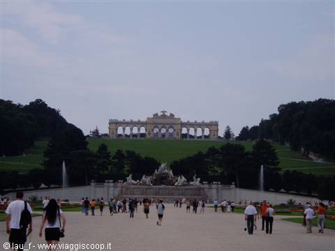 Tourists stroll through Schönbrunn gardens toward the Gloriette on the hill