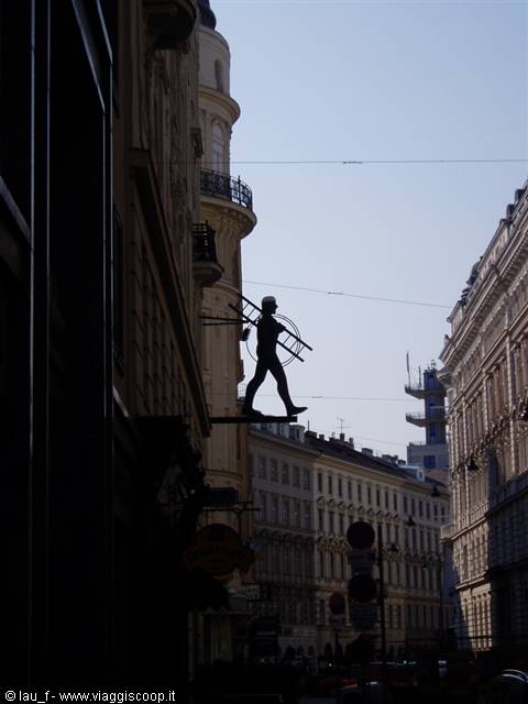 Metal chimney sweep sign above a Vienna street silhouetted against the sky