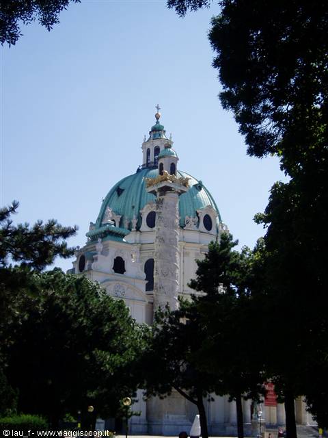 The green dome of Vienna's Karlskirche framed by tree branches