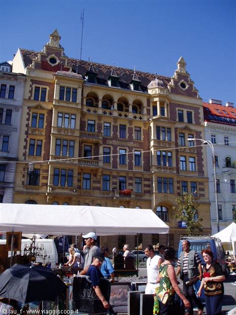 Flea market at Vienna's Naschmarkt, people browsing stalls in front of an Art Nouveau building