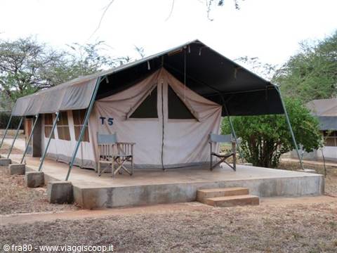 Beige safari tent on concrete platform with folding chairs