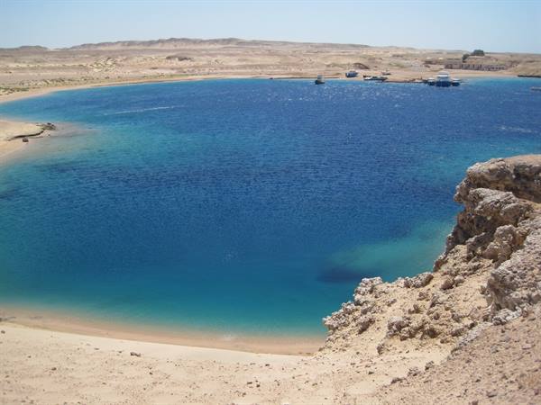turquoise bay between desert rocks, boats moored in the distance