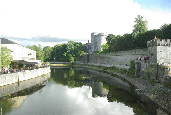 Kilkenny Castle reflects in the River Nore among walls and trees