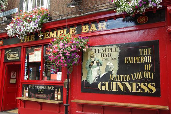 Red facade of the Temple Bar pub in Dublin, hanging flowers and Guinness signs
