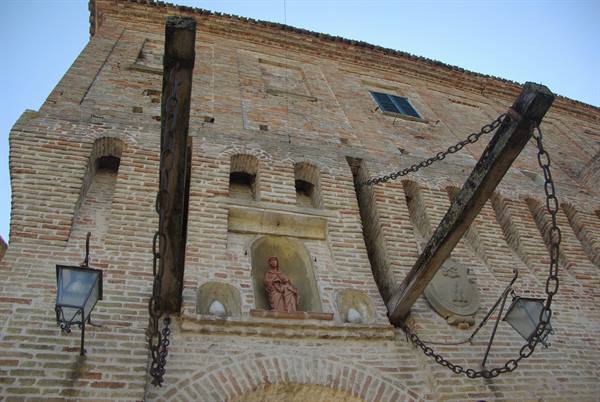 Brick facade with wooden drawbridge beams, iron chains and a statue niche