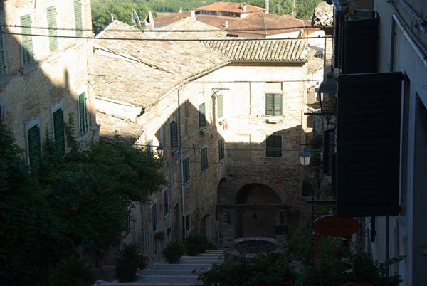 Stone staircase between old houses with brick roofs and green shutters