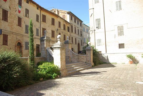 Brick rampart with stairs in front of stone houses, midday sun