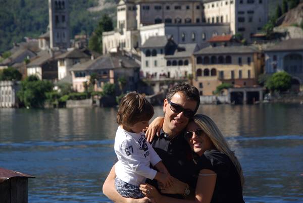 Couple holding their child by Lake Orta with San Giulio island behind