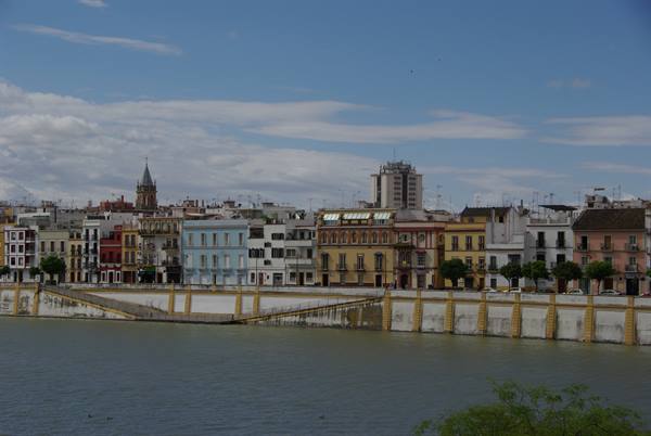 Colorful houses along the Guadalquivir river in Seville under cloudy sky