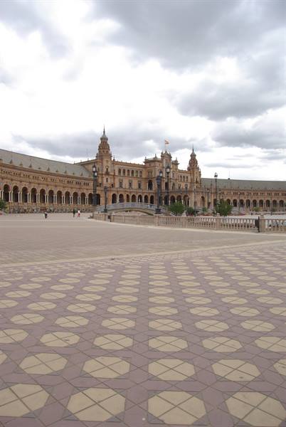Plaza de España in Seville, brick pavilion with arches, patterned tile pavement, cloudy sky