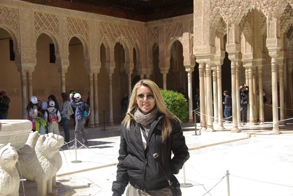 Smiling woman in the Court of the Lions, Alhambra, among marble arches and columns