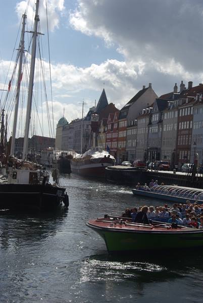 Tour boats crowded with visitors sailing Nyhavn canal past colorful townhouses