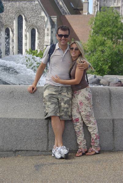 Couple in sunglasses hugging beside a fountain in front of Christchurch Cathedral