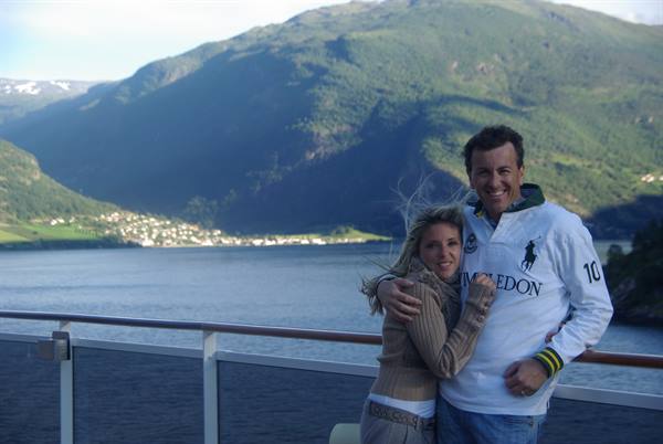 Smiling couple on a ship deck before a fjord and village