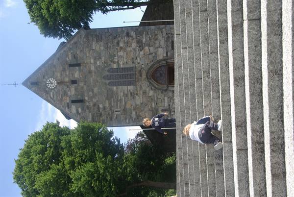 Children play on granite steps in front of a stone church with a clock
